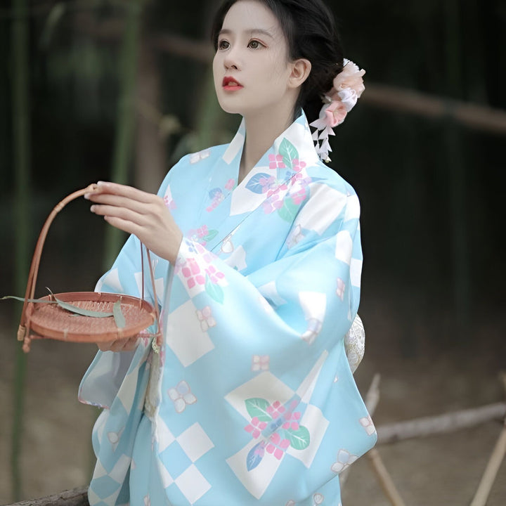 Femme portant un kimono bleu à motifs floraux et géométriques, tenant un panier en osier. Kimonos traditionnels japonais disponibles à l'achat.