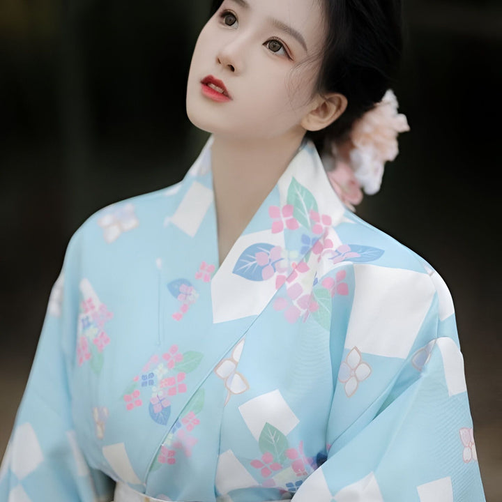 Femme portant un kimono bleu avec motifs floraux. Élégance et tradition japonaises. Découvrez notre collection de kimonos uniques.