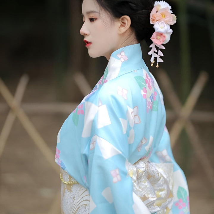 Femme portant un kimono bleu clair à motifs floraux. Vente de kimonos traditionnels et modernes pour femmes. Accessoires de cheveux fleuris. Mode japonaise authentique.