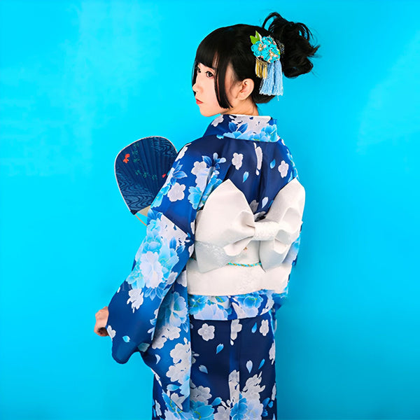 Femme portant un kimono bleu à fleurs avec un obi blanc. Elle a un éventail et une coiffure traditionnelle. Vêtements japonais traditionnels à vendre.