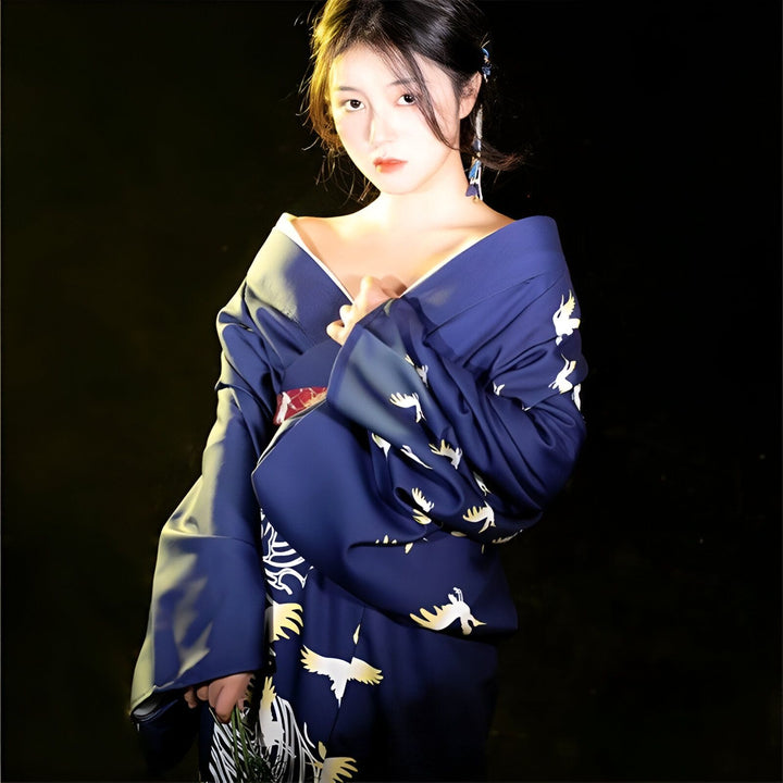 Jeune femme portant un kimono bleu marine orné de motifs de grues blanches. Vêtements japonais traditionnels. Boutique en ligne de kimonos pour femmes.