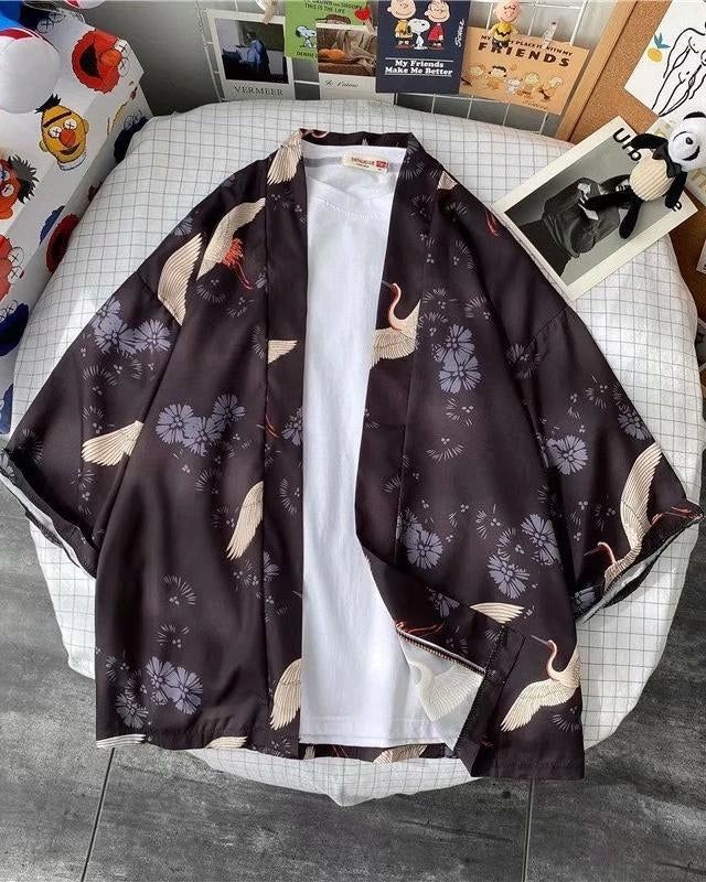 Kimono noir à motifs de grues et fleurs, présenté sur un lit. Vêtements de style japonais. Idéal pour un look unique et tendance. Découvrez notre collection de kimonos.