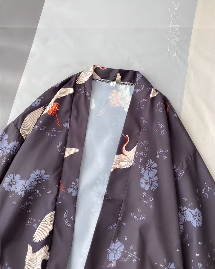 Kimono noir imprimé avec des motifs de grues blanches et de fleurs bleues. Vêtement traditionnel japonais, idéal pour un look élégant et original. Découvrez notre collection de kimonos uniques.