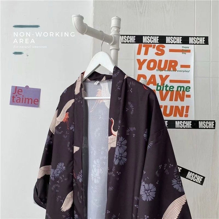 Kimono noir imprimé avec motifs de grues et fleurs, suspendu à un porte-manteau blanc. Vêtements japonais traditionnels à la mode. Boutique en ligne de kimonos.