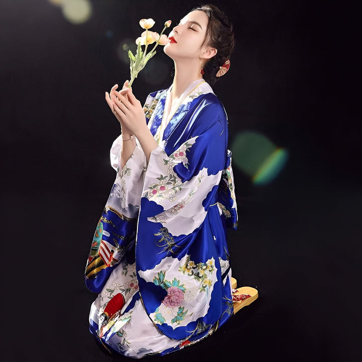 Femme en kimono bleu et blanc à motifs floraux, sentant des fleurs. Vente de kimonos authentiques.