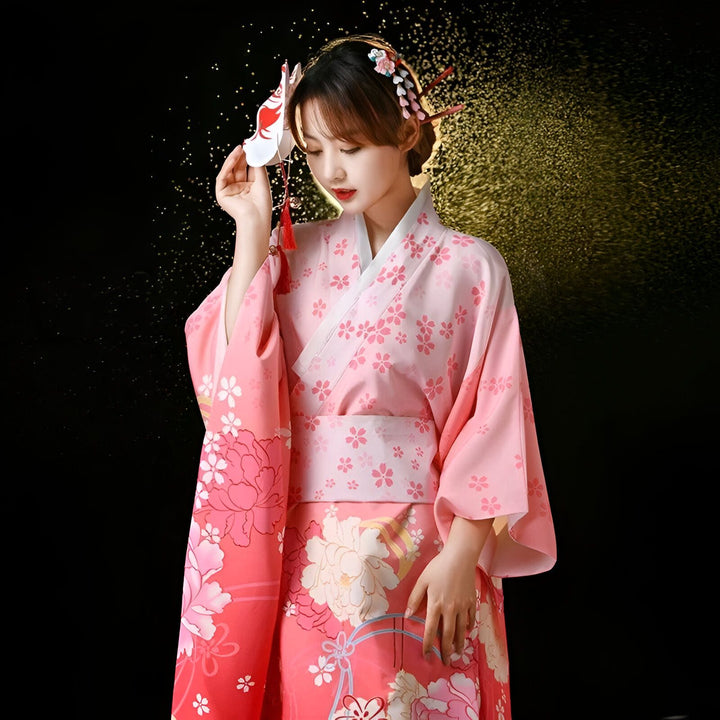 Femme portant un kimono rose à motifs floraux, tenant un masque de renard. Kimonos traditionnels japonais à vendre.