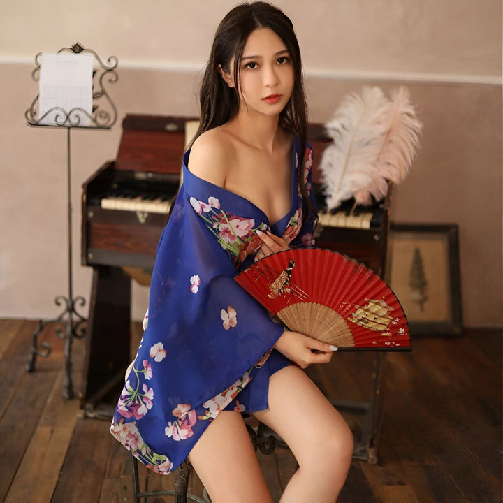 Femme asiatique en kimono bleu fleuri tenant un éventail rouge. Vêtements de style japonais, kimono traditionnel revisité. Notre collection de kimonos pour un look élégant et unique.
