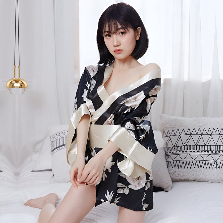 Femme portant un kimono en soie noire à motifs floraux, parfaite pour se détendre à la maison. Découvrez notre collection de kimonos élégants et confortables.