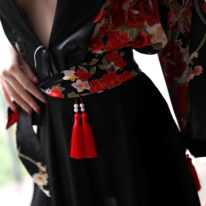 Kimono noir avec motifs floraux rouges. Détail de la ceinture obi et des pompons rouges. Vêtements japonais traditionnels en vente.