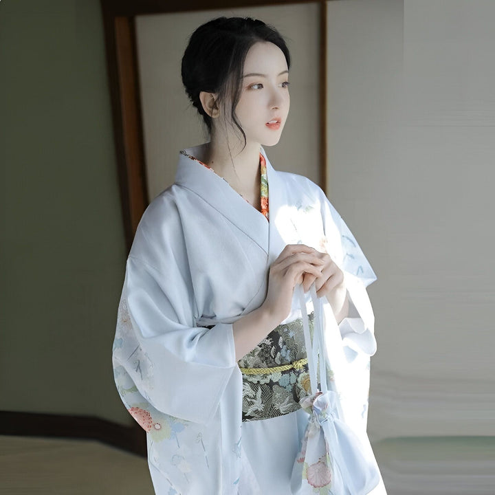 Femme en kimono bleu clair avec ceinture obi et sac assorti. Vêtements traditionnels japonais. Kimonos à vendre.