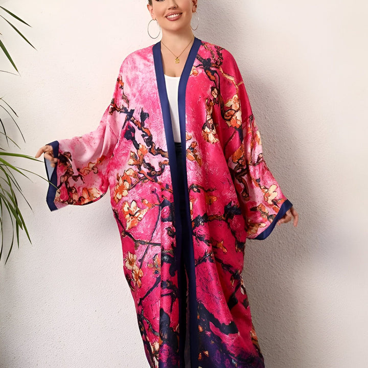 Femme souriante portant un kimono rose à motifs floraux avec bordure bleu marine. Vêtements de style japonais. Notre collection de kimonos élégants.
