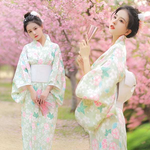 Deux femmes en kimonos à motifs floraux devant des cerisiers en fleurs. Kimonos japonais traditionnels à vendre.