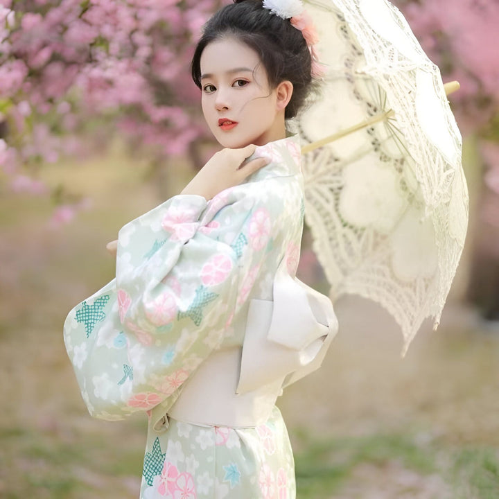 Jeune femme portant un kimono fleuri et tenant une ombrelle en dentelle. Kimonos en vente en ligne.