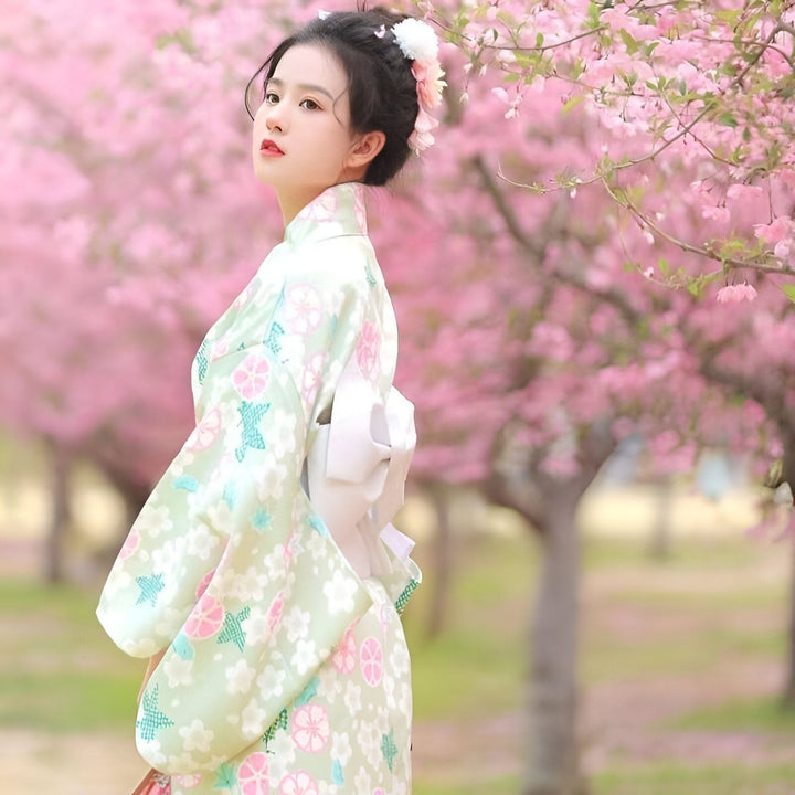 Femme portant un kimono fleuri sous les cerisiers en fleurs. Découvrez notre collection de kimonos traditionnels et modernes. Vêtements japonais authentiques.