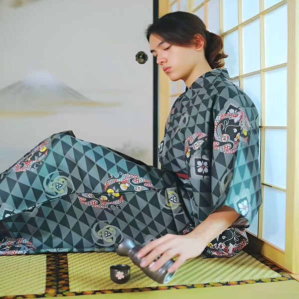 Homme en kimono traditionnel assis sur un tatami, versant du saké. Motifs géométriques et floraux sur le kimono gris et turquoise. Vente de kimonos japonais authentiques.