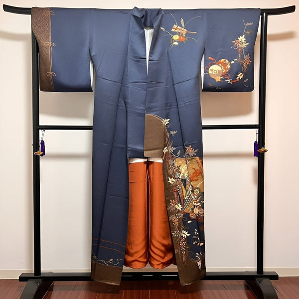 Kimono bleu marine avec motifs floraux et géométriques, suspendu sur un portant. Vêtement traditionnel japonais, idéal pour une tenue élégante et unique. Découvrez notre collection de kimonos.