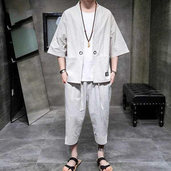 Homme portant un ensemble kimono décontracté gris clair : veste kimono courte à manches larges et pantalon assorti. Collier de perles, sandales. Vêtements japonais modernes en vente.