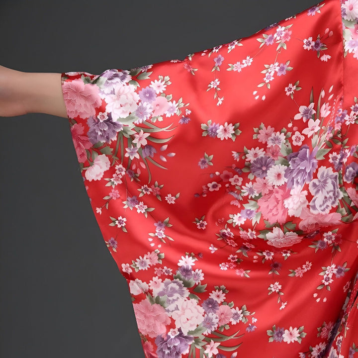 Détail d'un kimono rouge en satin avec des motifs floraux roses et violets. Vêtement traditionnel japonais, parfait pour une tenue élégante et confortable.