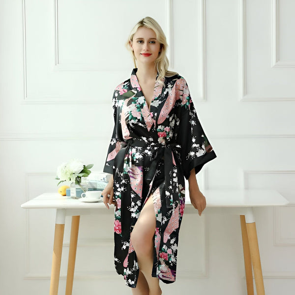 Femme blonde portant un kimono noir à motifs floraux roses et blancs. Vente de kimonos pour femmes. Peignoir style japonais. Idée cadeau kimono pour elle.