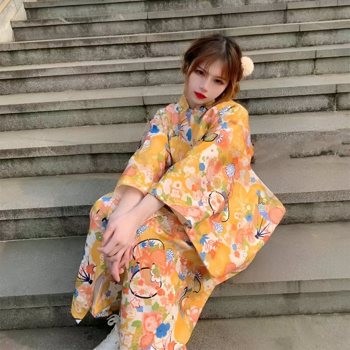 Femme assise sur des marches en kimono jaune à motifs floraux. Kimonos traditionnels japonais en vente.