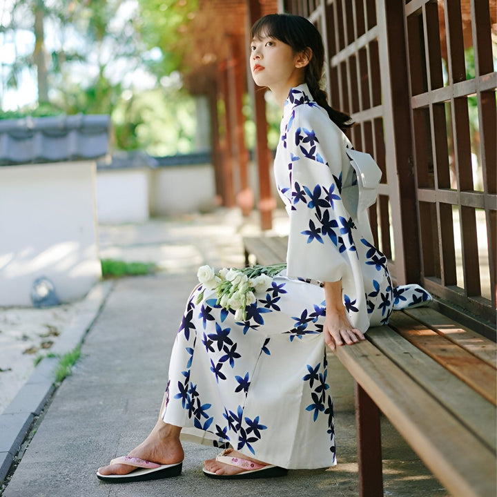 Femme assise portant un kimono fleuri blanc et bleu. Vente de kimonos japonais traditionnels et modernes pour femmes. Élégance et style japonais.