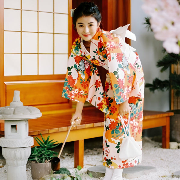 Femme souriante en kimono floral traditionnel. Vêtements japonais authentiques, motifs floraux orange et blanc. Kimonos de haute qualité à vendre. Élégance japonaise.