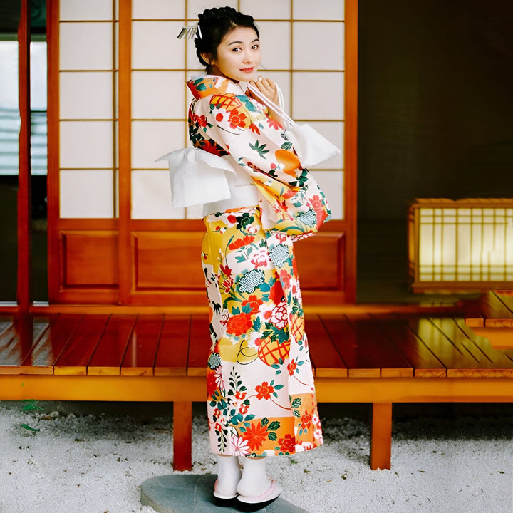 Femme portant un kimono japonais traditionnel à motifs floraux, devant une porte coulissante en bois. Kimonos de haute qualité disponibles à l'achat.