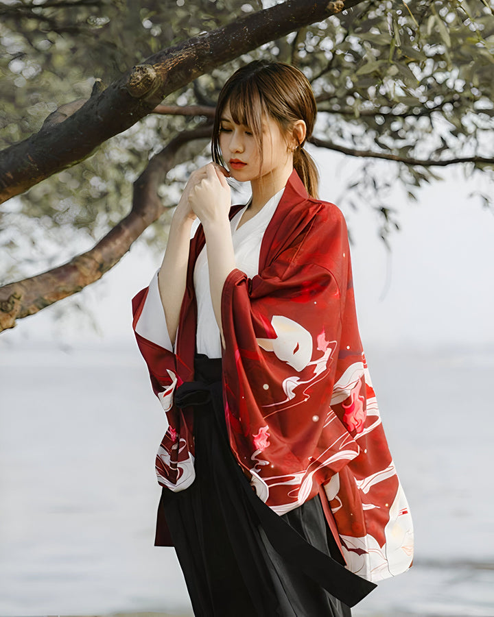 Femme portant un kimono rouge avec motifs renard et une jupe noire traditionnelle. Vêtements japonais authentiques, style élégant. Collection de kimonos uniques pour un look traditionnel et moderne.