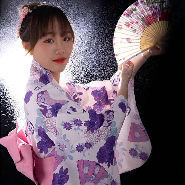 Femme souriante en kimono fleuri, tenant un éventail. Kimonos traditionnels japonais à vendre.