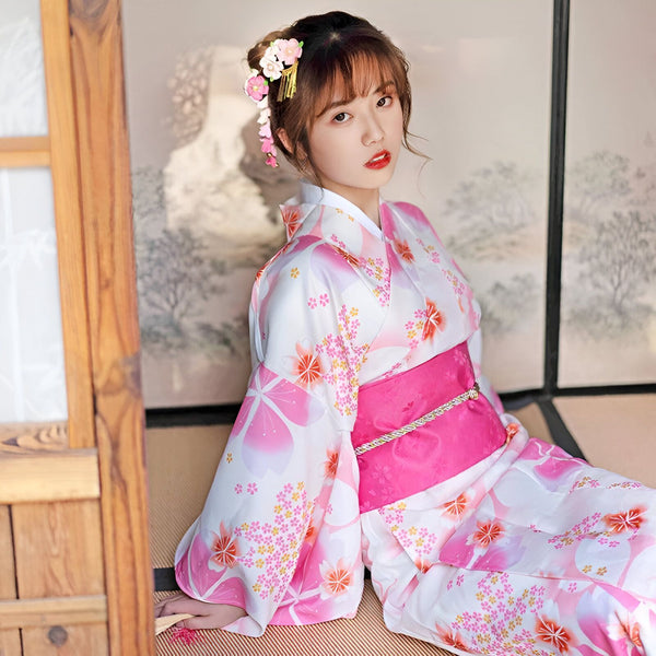 Femme asiatique portant un kimono blanc et rose à motifs floraux. Vente de kimonos traditionnels japonais pour femmes. Élégance et style japonais authentique.