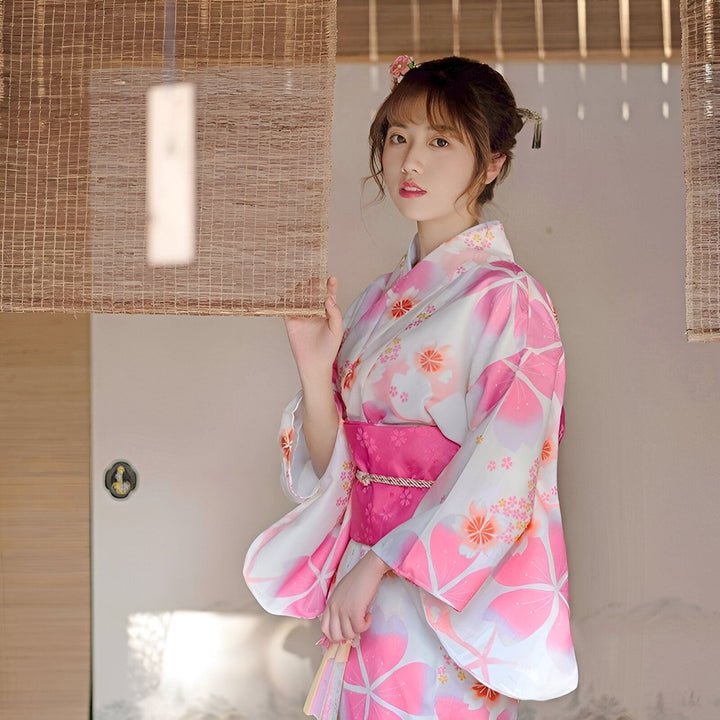 Femme portant un kimono à fleurs rose et blanc. Vente de kimonos traditionnels et modernes.