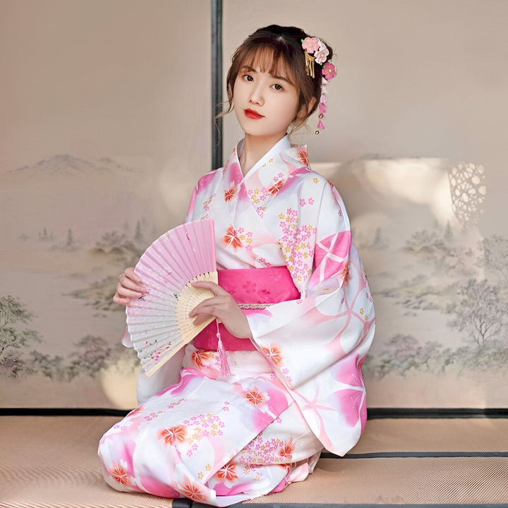 Femme portant un kimono blanc et rose à motifs floraux, tenant un éventail rose. Vêtements traditionnels japonais. Kimonos à vendre.