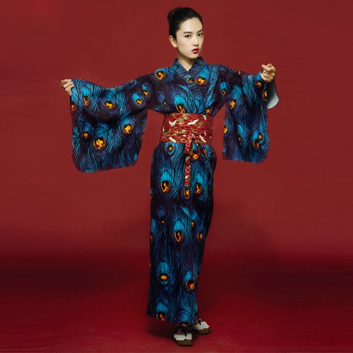 Femme portant un kimono bleu à motifs de plumes de paon avec une ceinture rouge. Vêtements japonais traditionnels. Kimono à motifs de plumes. Vente de kimonos en ligne.