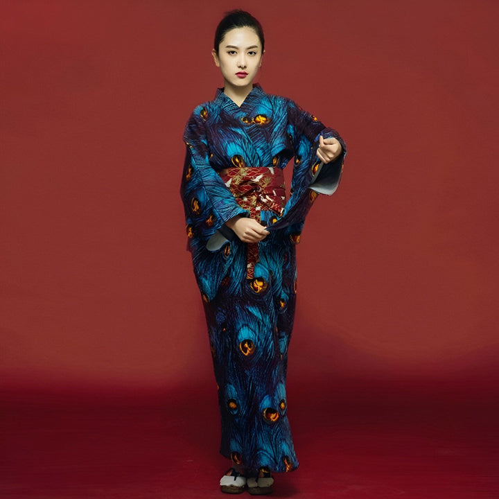 Femme portant un kimono bleu à motifs de plumes de paon avec une ceinture obi rouge. Vêtements traditionnels japonais en vente.