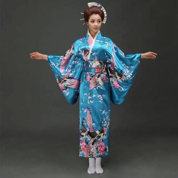 Femme portant un kimono traditionnel bleu avec des motifs floraux roses. Découvrez notre collection de kimonos authentiques.
