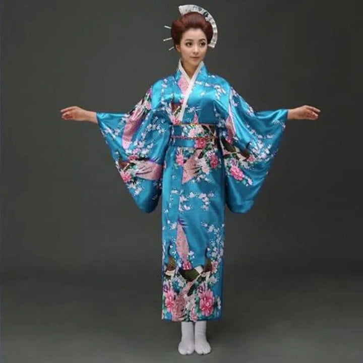 Femme portant un kimono traditionnel bleu avec des motifs floraux roses. Découvrez notre collection de kimonos authentiques.