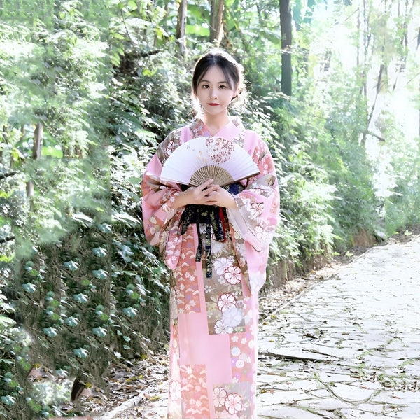 Jeune femme en kimono rose fleuri avec éventail. Découvrez notre collection de kimonos traditionnels et modernes. Élégance et raffinement japonais.