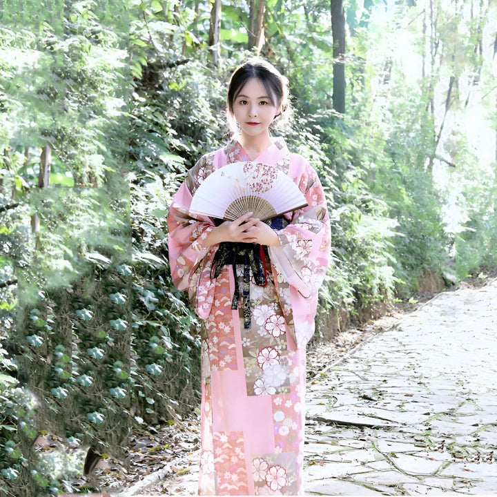Jeune femme en kimono rose fleuri avec éventail. Découvrez notre collection de kimonos traditionnels et modernes. Élégance et raffinement japonais.