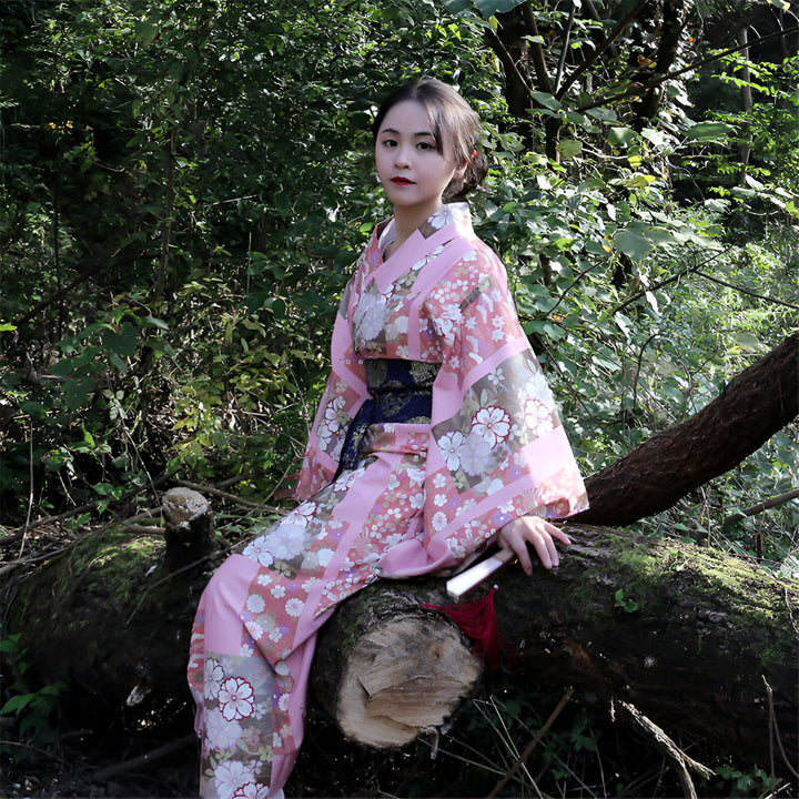 Femme portant un kimono rose à motifs floraux dans la nature. Kimonos traditionnels japonais disponibles à l'achat.