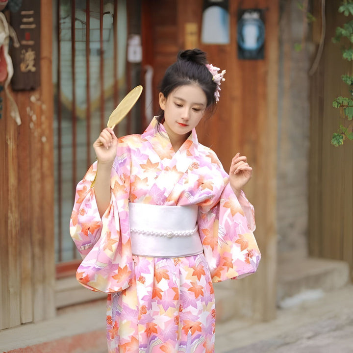 Femme portant un kimono floral rose et orange, éventail en main. Kimono traditionnel japonais à vendre.