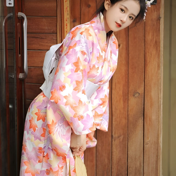 Jeune femme portant un kimono traditionnel à motifs floraux roses et orange. Kimonos japonais de haute qualité à vendre dans notre boutique.
