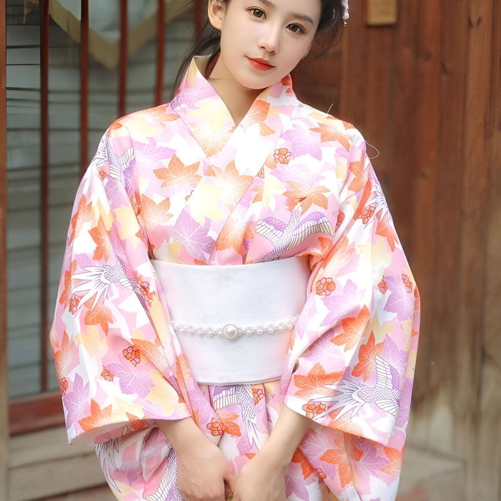 Jeune femme en kimono rose à motifs floraux et oiseaux. Vente de kimonos traditionnels et modernes. Découvrez notre collection unique !