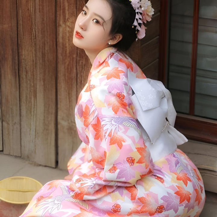 Femme portant un kimono rose à motifs floraux et d'oiseaux. Vêtements traditionnels japonais à vendre. Coiffure ornée de fleurs.