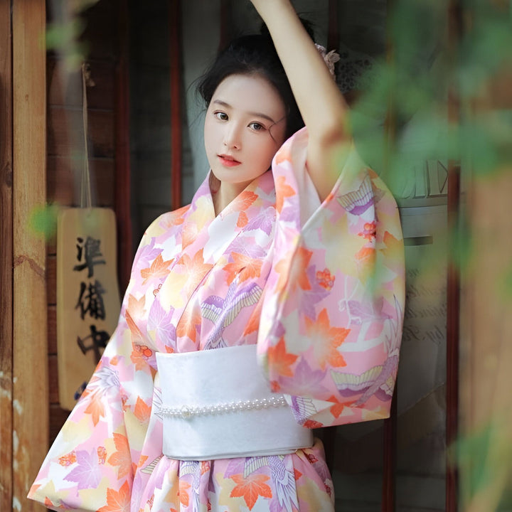 Jeune femme portant un kimono fleuri rose. Kimonos traditionnels japonais en vente.