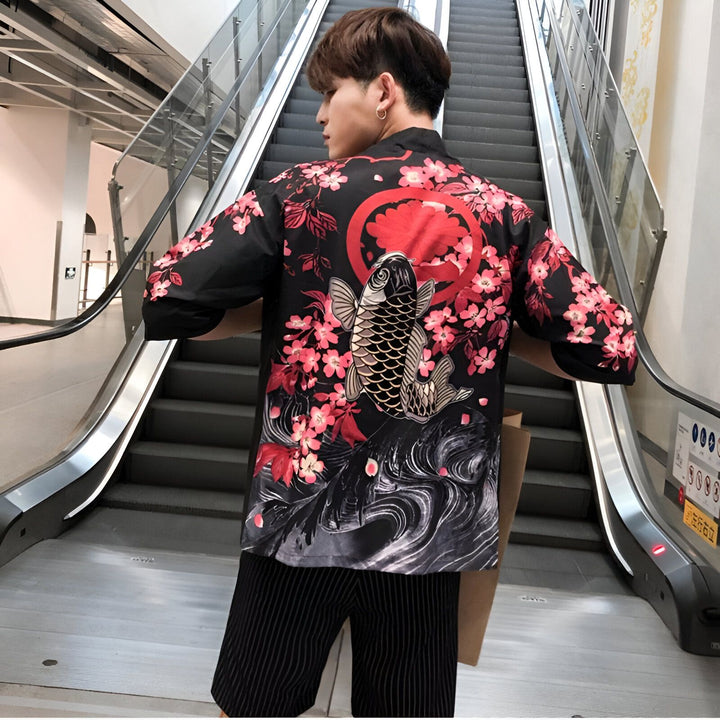Homme portant un kimono noir avec motif de poisson carpe et fleurs de cerisier rouges. Vêtements traditionnels japonais revisités. Mode kimono pour hommes.