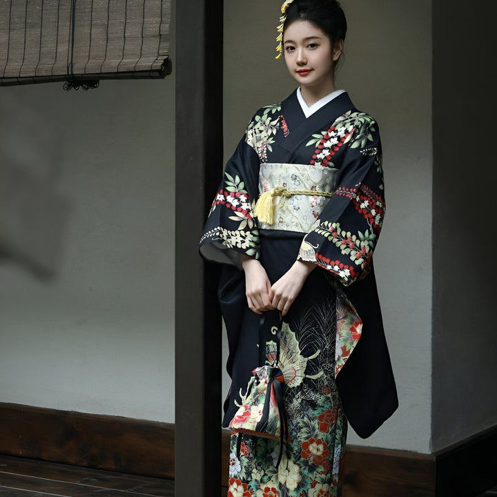 Femme portant un kimono noir orné de motifs floraux colorés et d'une ceinture obi traditionnelle. Élégance japonaise et style kimono authentique. Découvrez notre collection de kimonos uniques.