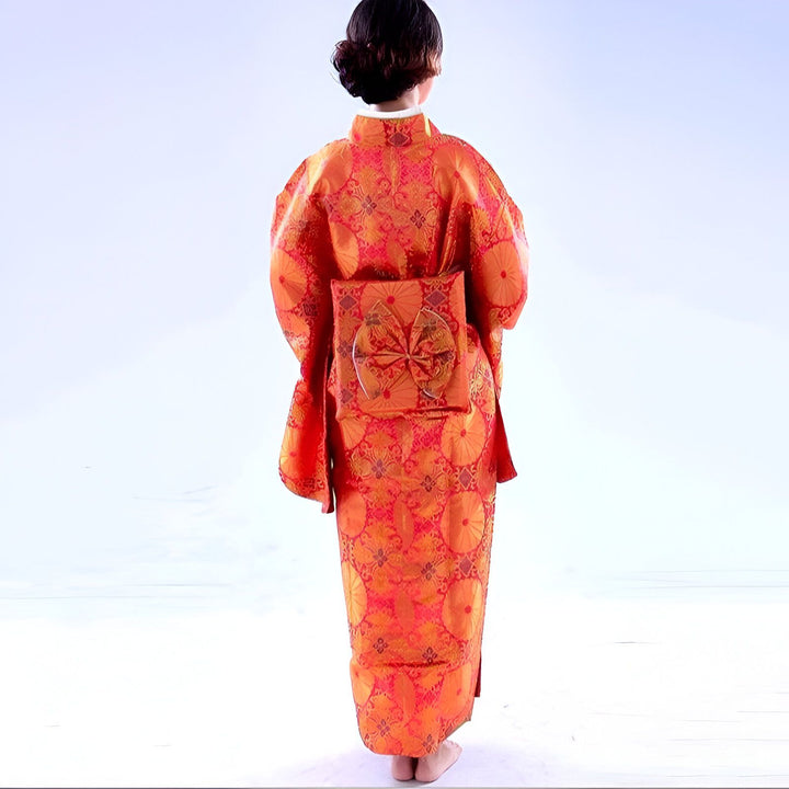 Femme portant un kimono orange traditionnel japonais avec motif floral et obi élaboré dans le dos. Vêtements japonais.