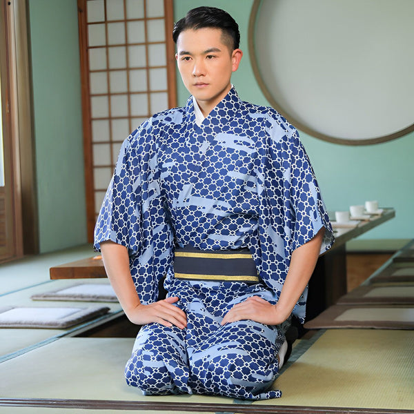 Homme asiatique à genoux portant un kimono bleu à motifs géométriques avec une ceinture obi noire et dorée. Vente de kimonos japonais traditionnels et modernes.