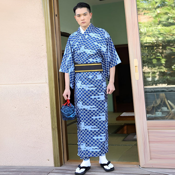 Homme portant un kimono japonais bleu avec motifs, tenant un sac assorti. Vente de kimonos traditionnels pour hommes. Découvrez notre collection de kimonos authentiques.