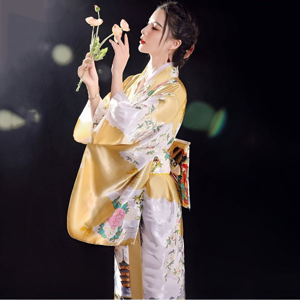 Femme élégante en kimono japonais doré et blanc à motifs floraux, tenant une fleur. Vente de kimonos traditionnels et modernes.